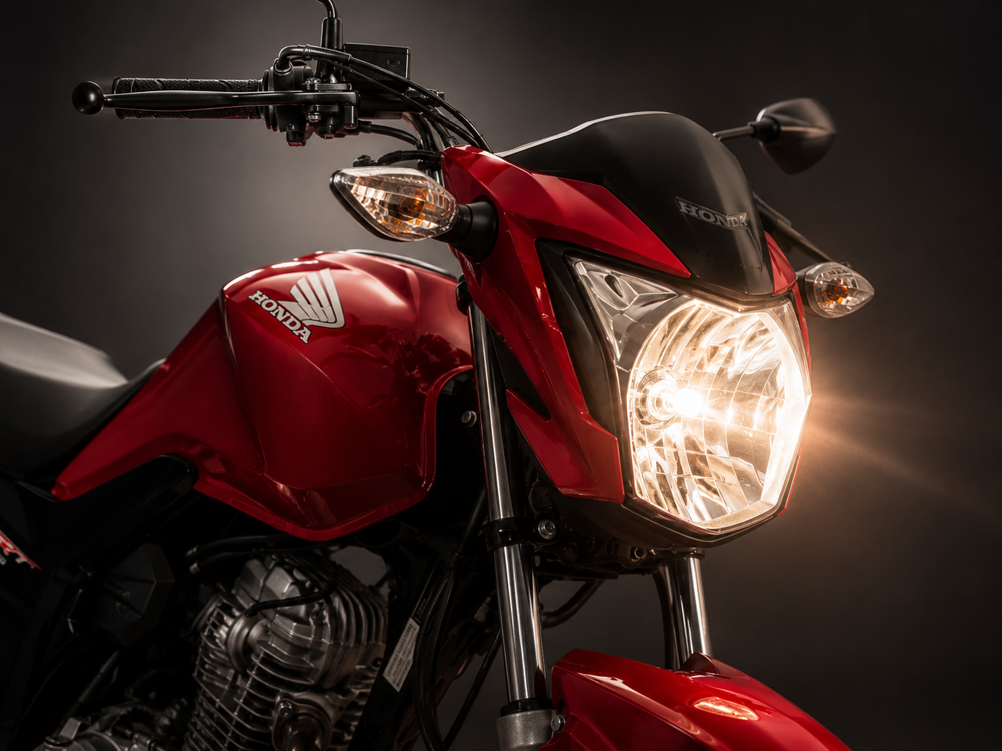 Farol aceso de uma Honda CG 160 vermelha em estúdio